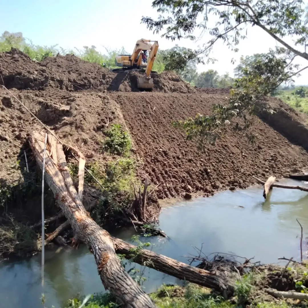 Excavadora conformando un talud junto al agua