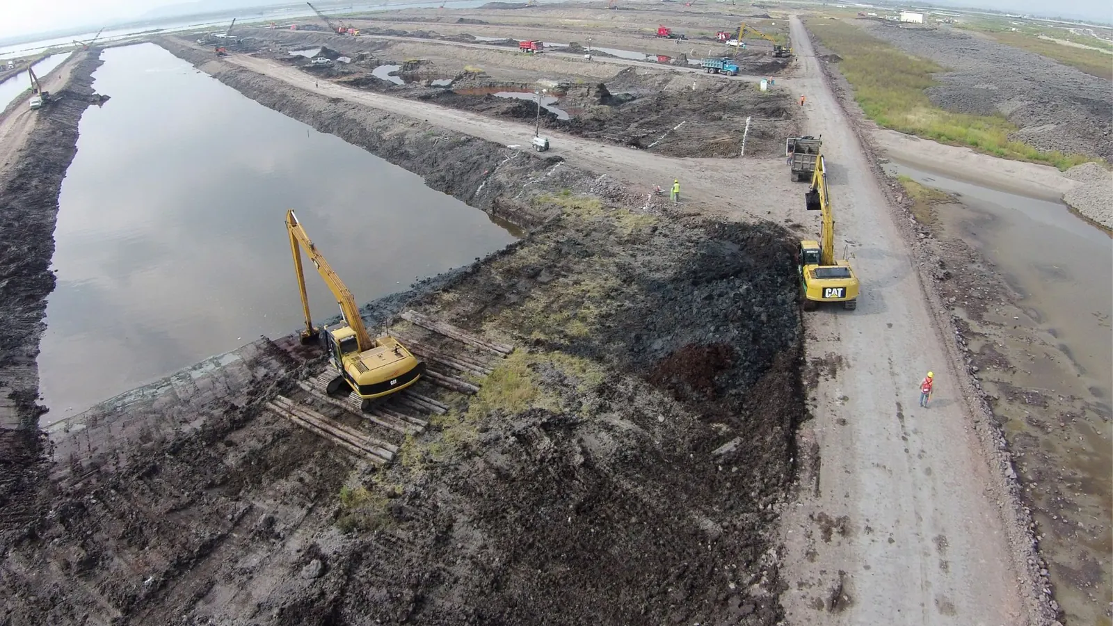 Excavadoras de brazo largo trabajando junto a un cuerpo de agua